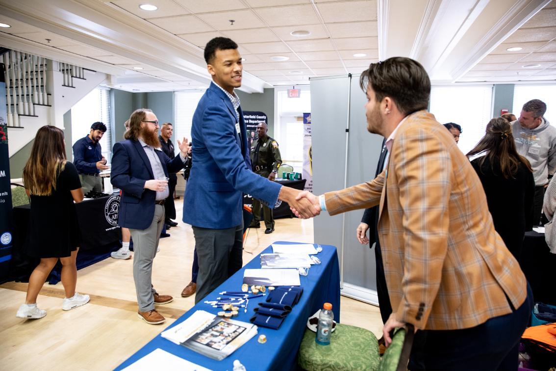 Student shaking hands with an employer during a career fair